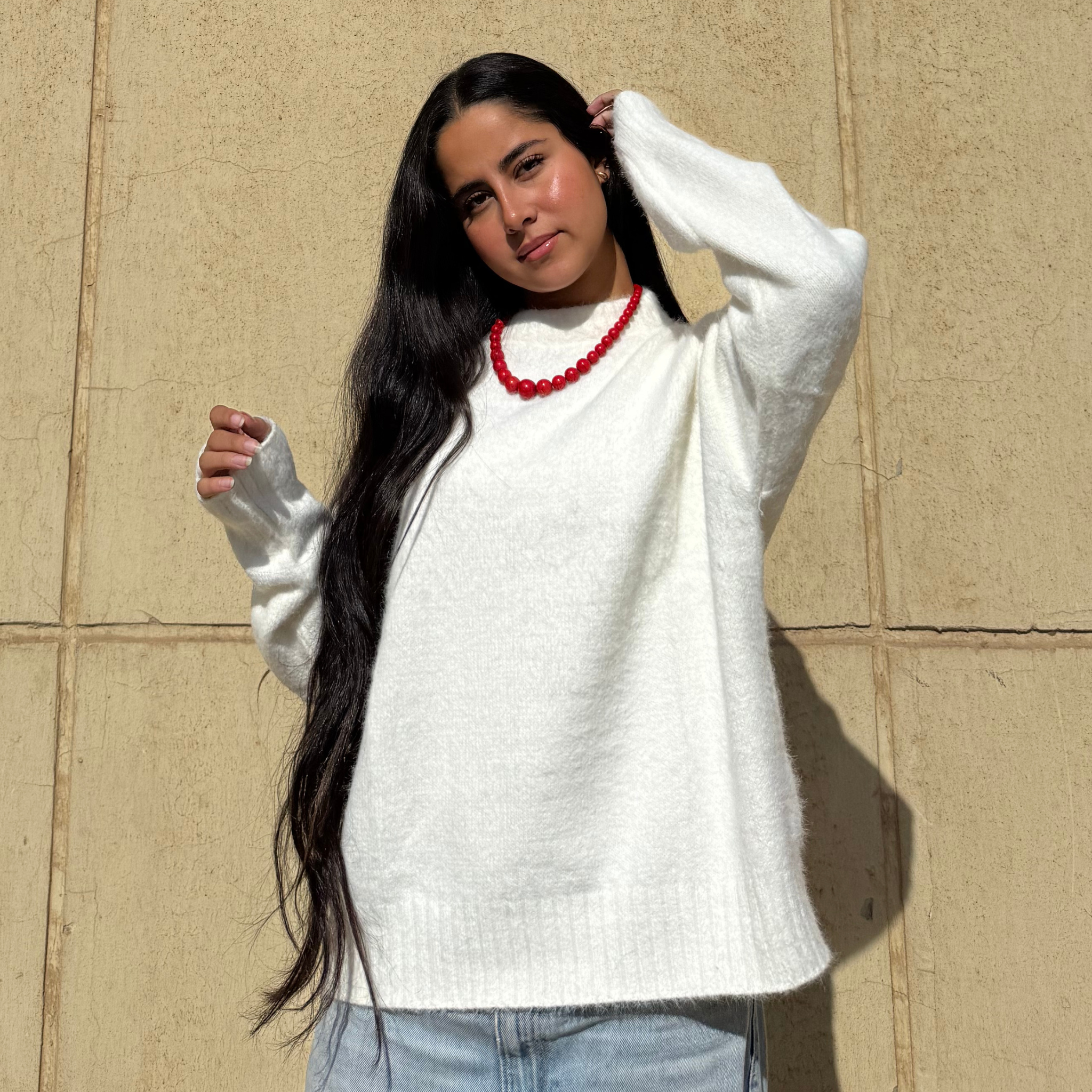 Woman wearing a white sweater against a beige wall
