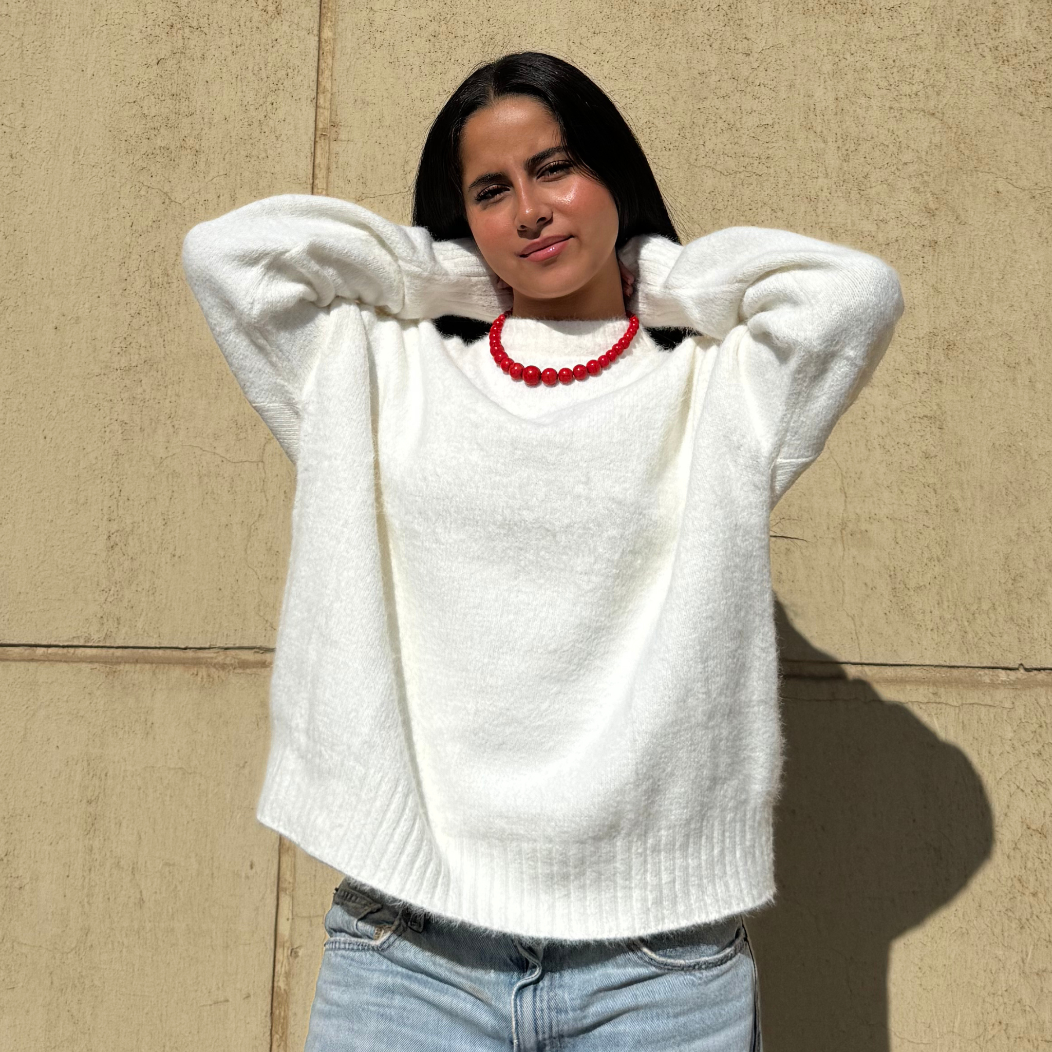 Woman wearing a white sweater against a beige wall