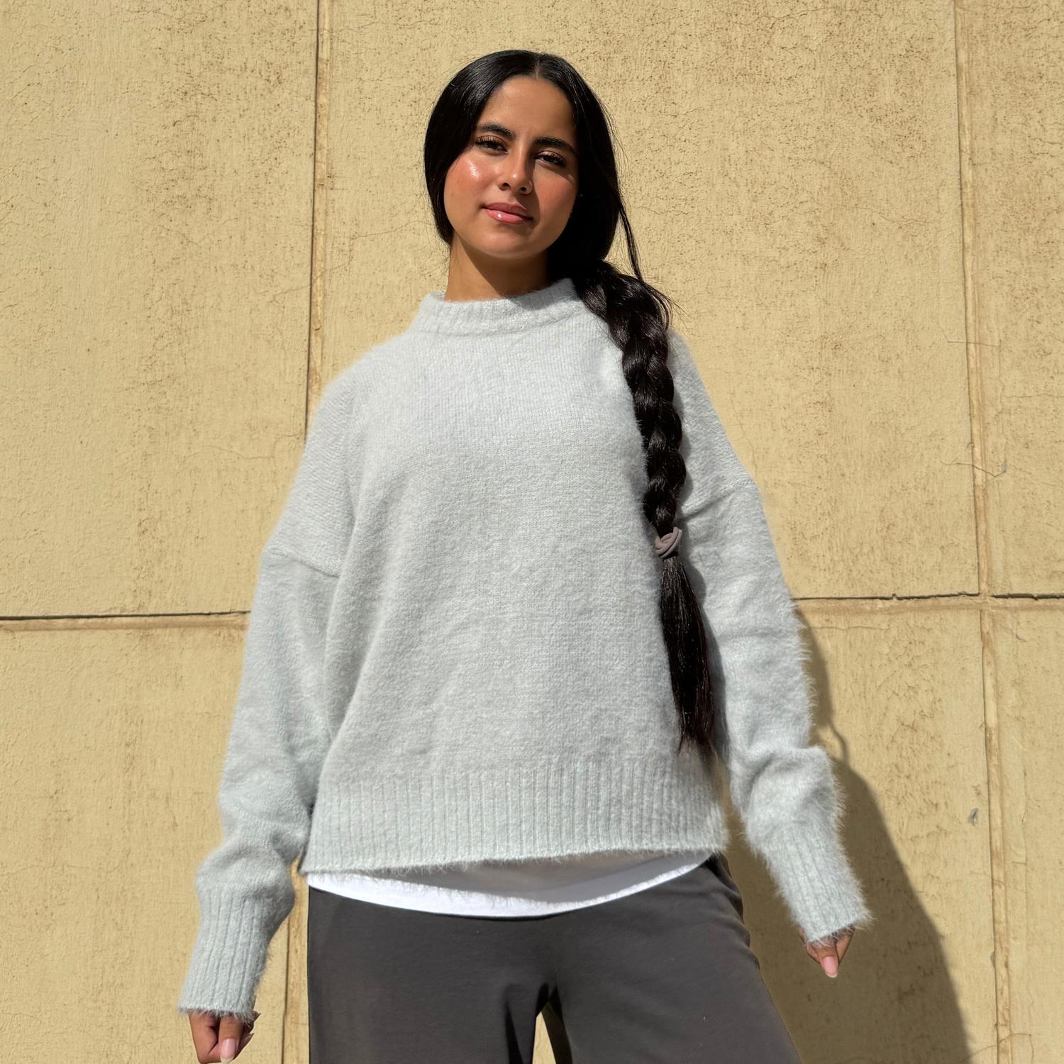 Woman wearing a light gray sweater against a beige wall